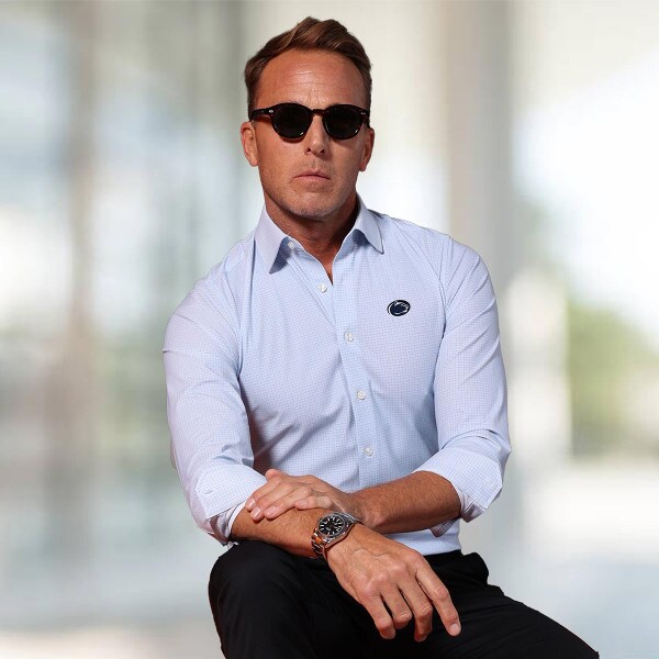 model wearing men's long sleeve button down dress shirt with embroidered Penn State Athletic Logo on left chest